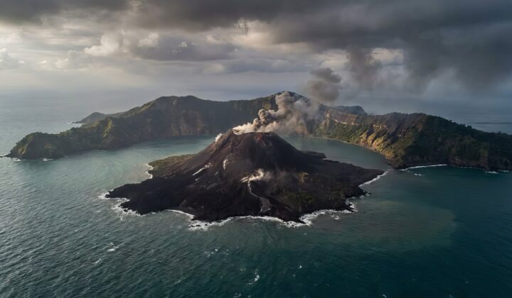 Anak krakatau volcano erupting from the ocean, spewing smoke and ash into the cloudy sky, displaying raw power and dynamic natural geological activity in indonesia
